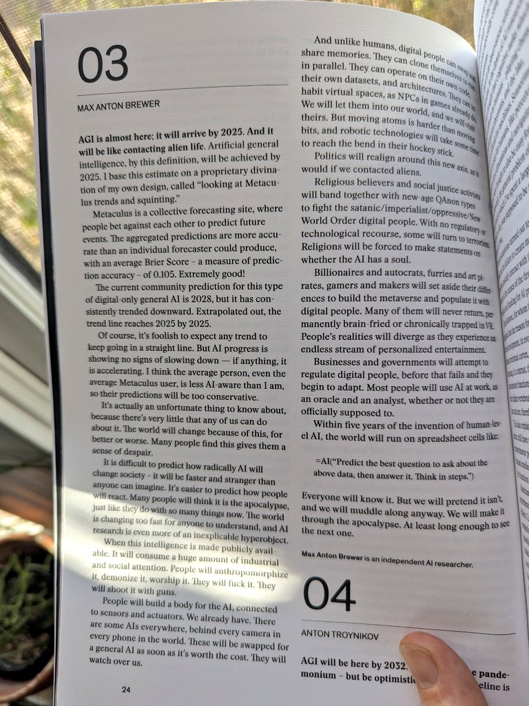 An open book page showing two articles: "03" by Max Anton Brewer on AI's 2025 arrival and societal impact, and "04" by Anton Troynikov on AI's 2025 optimism, with a finger pointing to the page number 24.